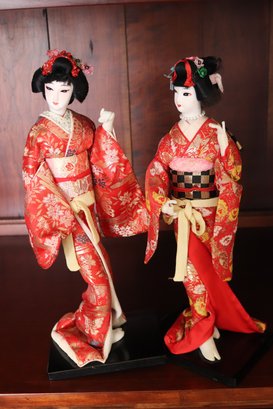 Two Japanese Geisha Dolls With Painted Faces And Silk Kimonos