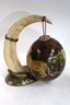 Two Decorative Painted Ostrich Eggs With Safari Scenes From South Africa Held On By A Faux Tusk