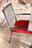 Outdoor Square Aluminum Table And Four Arm Chairs With Red Cushions.