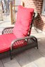 An Adjustable Weather Wicker Lounge Chair With Red Cushions.