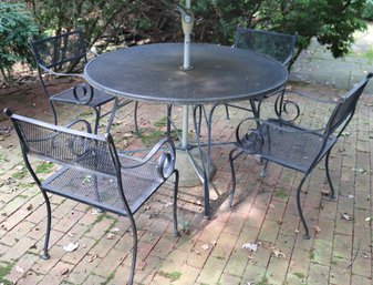 A Round Iron Outdoor Table And Four Armchairs.