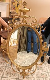 An Elegant And Graceful Decorative Arte Oval Regency Style Beveled Gilded Mirror.