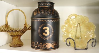 A Vintage Look Gilt Decorated Tole Tea Caddy And 2 Amber Glass Pieces.