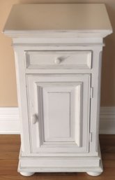 Small White Painted Nightstand With Molded Cabinet Door And One Drawer.