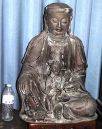 Large Metal Buddha Statue With Downcast Gaze At Child On His Lap