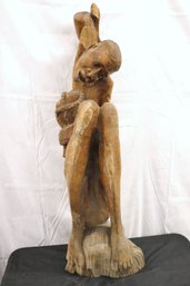 Carved Wood Haitian Statue Of Seated Man With His Knees Pulled Up To His Chest.