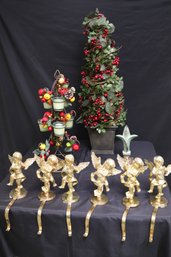 Assortment Of Christmas Decorations With Tall Topiary, Candle Holder, And Brass Stocking Holders.