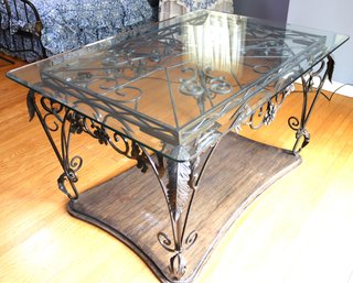 Heavy Wrought Iron Table With A Glass Top With Rounded Edges And A Beveled Glass Top.