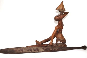 Carved Wood Sculpture Of A Man Drinking From A Conch Shell Includes A Carved Wood Paddle With Etching.