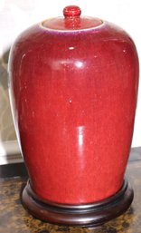 A Tall, Vintage Oxblood Jar With Light Colored Rim, And Lid