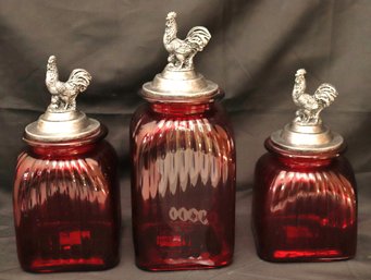 Set Of 3 Large Decorative Red Glass Canisters With Rooster Accented Lids Ranging In Size
