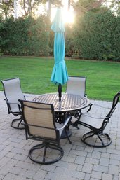 Round Metal Outdoor Dining Table With Teal Colored Umbrella And 4 Chairs.
