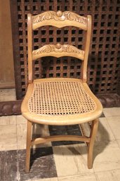 A Vintage Victorian Caned Chair In Honey Color Wood With Carved Seatback
