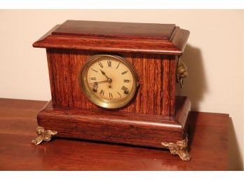 ANTIQUE ROSEWOOD SETH THOMAS MANTLE CLOCK WITH BRASS FEET AND LION HEAD ACCENTS ON SIDE