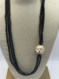 Black Beaded Necklace With A Silver Clasp And A Decorative Monkey
