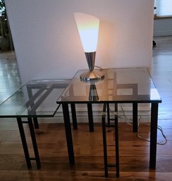 2 Stylish Tempered Glass Tables With Black Metal Frame Paired With A Modern Touch Lamp