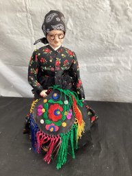 Old Woman Sitting On Chair Doing Embroidery