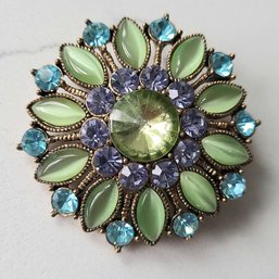 VINTAGE GOLDTONE FLORAL BROOCH WITH GREEN, BLUE & PURPLE STONES