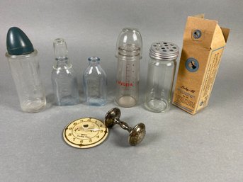 Fun Collection Of Vintage Baby Nursing Items Including A Timer, Glass Bottles, Bottle Caps, & Rattle