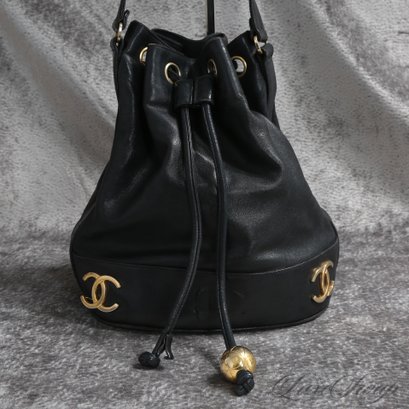 AN EXCEPTIONAL AND RARE EARLY 1990S AUTHENTIC CHANEL BLACK LEATHER DRAWSTRING BAG WITH GOLD CC'S AND CHAIN