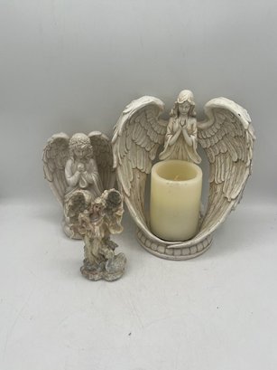 A Group Of Three Angels Figurines One Candle