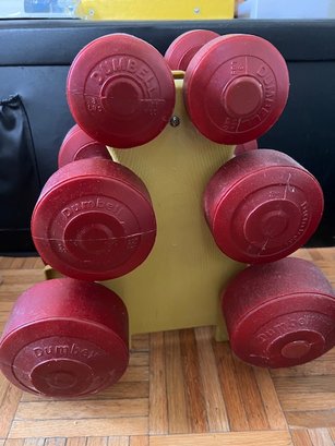 A Set Of 6 Dumb Bell Weights On Rack