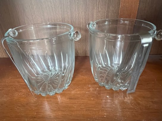 A Pair Of Glass Ice Buckets With Ice Tongs