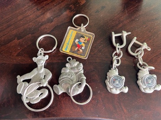 A Group Of Disney Key Chains And Compasses