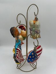 A Group Of Glass Hand Painted Christmas Ornaments On Stand