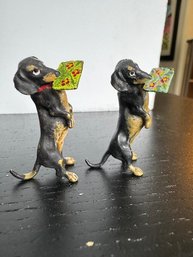 A Pair Of Dachshunds Holding Letters In Their Mouths