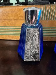 A Pair Of Cobalt Blue Bottles With Silver Toned Icons For Holy Water