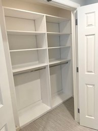 White Adjustable Closet System With Shelves And Metal Poles