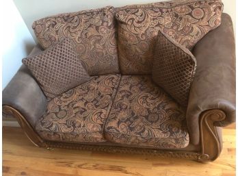 Love Seat With Patterned Cushions And 2 Decorative Pillows. Engraved Wood And Brown Faux Leather Base