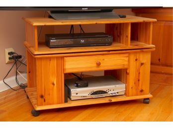 A Pine TV Stand With Rotating Top On Wheels