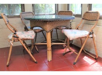 A Glass Top Rattan Table With Four Matching Chairs