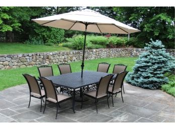 A Cast Metal Outdoor Table With Matching Chairs And Umbrella