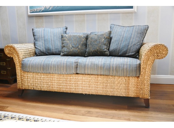 A Custom Covered Rattan Sofa With Coordinating Throw Pillow