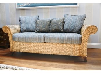 A Custom Covered Rattan Sofa With Coordinating Throw Pillow