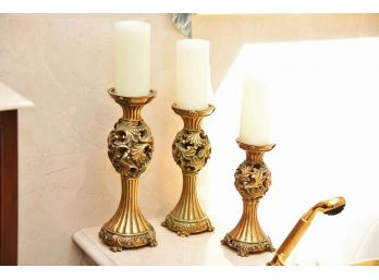 A Trio Of Gold Tone Candle Sticks With Flameless Candles