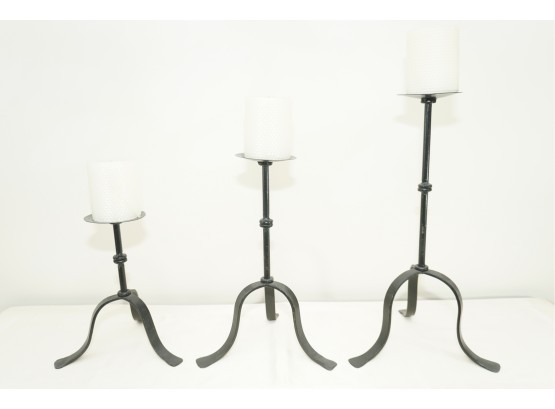 A Trio Of Wrought Iron Tripod Candle Holders With Rolled Wax Candles