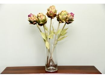 A Grouping Of Faux Artichokes On Stems In Glass Vase
