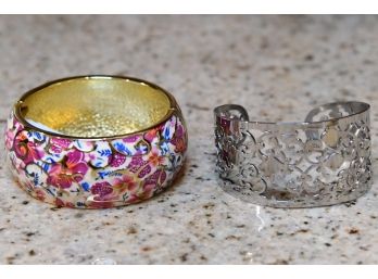 An Enamel Bracelet With Floral Motif And A Ornate Silver Colored Bracelet